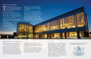 A 2 page program spread with a large, nighttime image of the university's library building, and information about the university's coat of arms.
